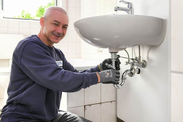 Handwerker repariert das Abflussrohr am Waschbecken.