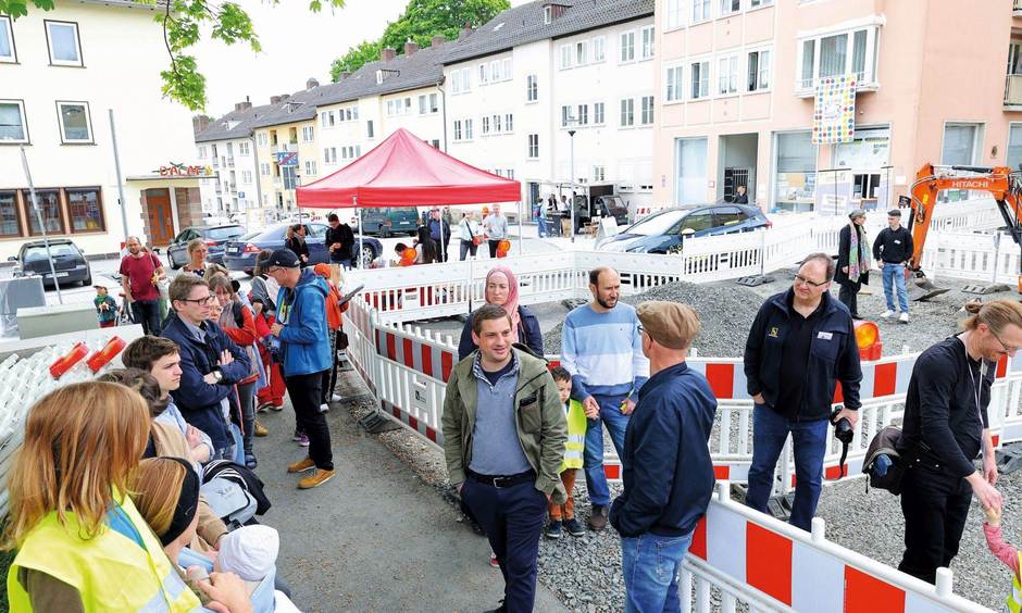 Eine Gruppe von Menschen steht binnen eine Baustelle auf einer Straße.