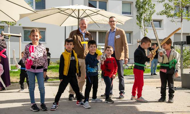 Zwei Erwachsene und viele Kinder mit Luftballonfiguren, alle lachen