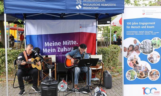 Zwei Musiker mit Gitarre in einem Pavillon mit Plakaten