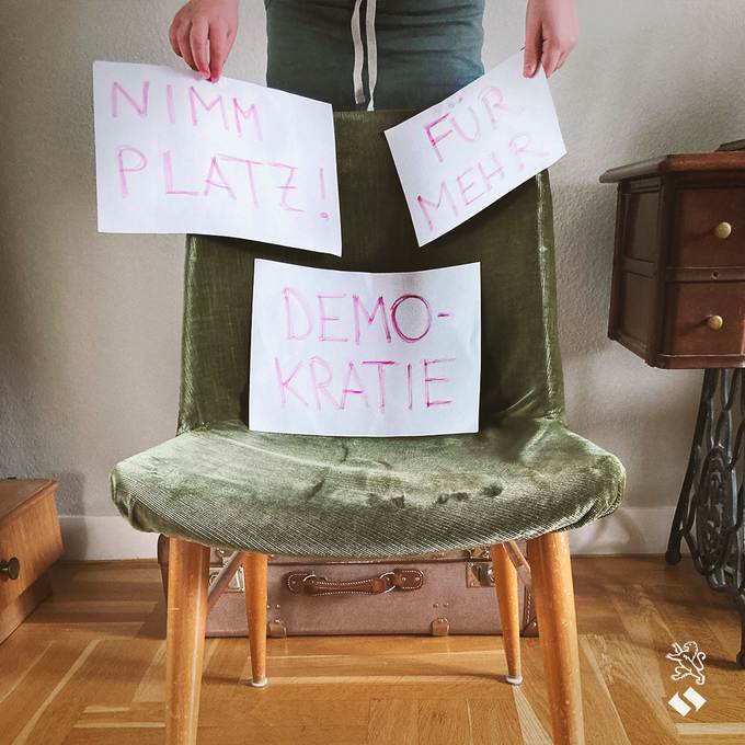 Stuhl mit drei Zetteln und der Aufschrift "Nimm Platz für mehr Demokratie"
