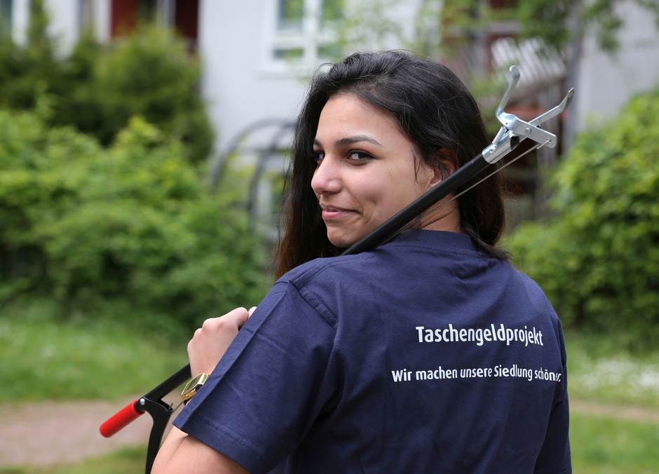 Eine junge Frau hat eine Müllzange in der Hand.