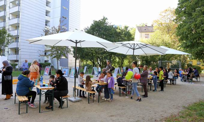 Menschen sitzen unter Schirmen auf Bierbänken.