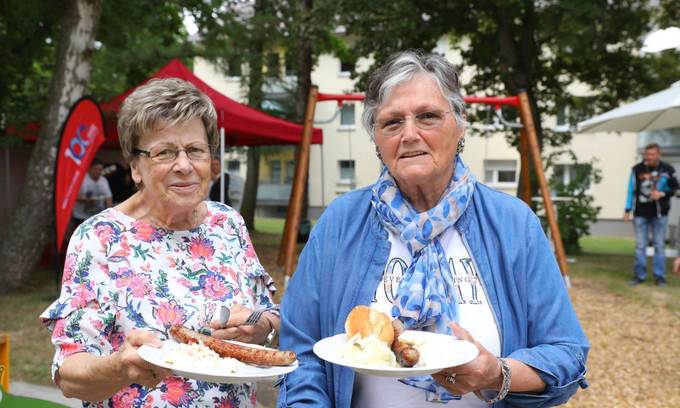 Zwei ältere Frauen mit Tellern, Bratwurst und Brötchen