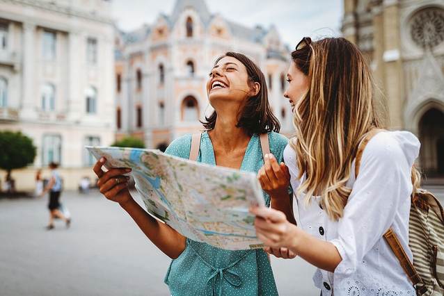 Zwei Frauen stehen in der Stadt und schauen auf einen Stadtplan.
