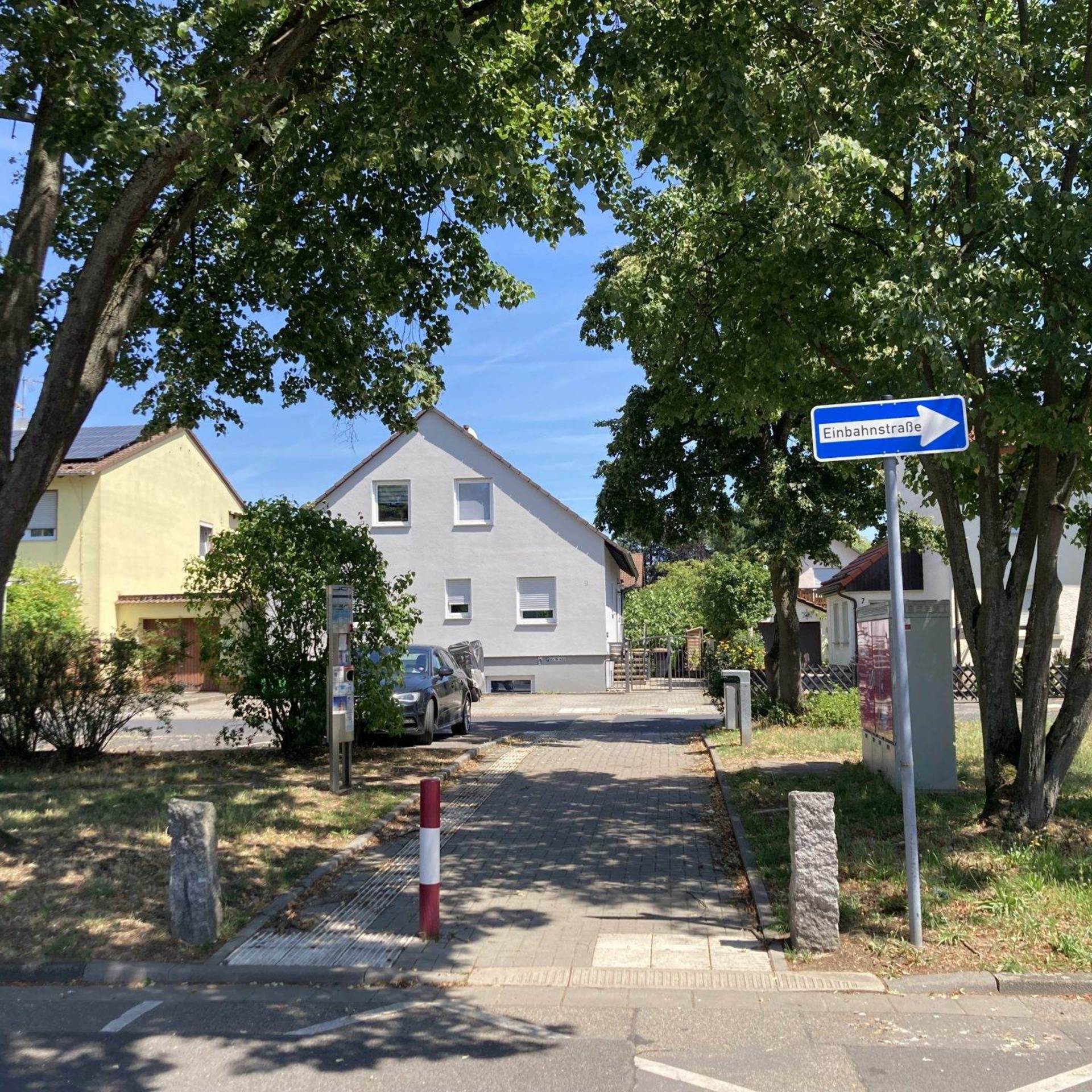 Grünstreifen in einem Wohngebiet mit Durchgang und Einbahnstraßenschild