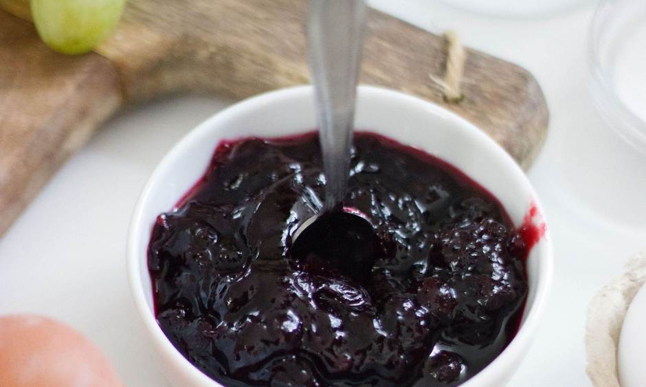 Rote Marmelade in einem Schälchen mit Löffel.