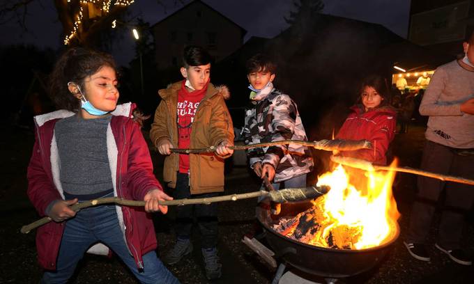 Vier Kinder halten ihre Stockbrote über das Feuer