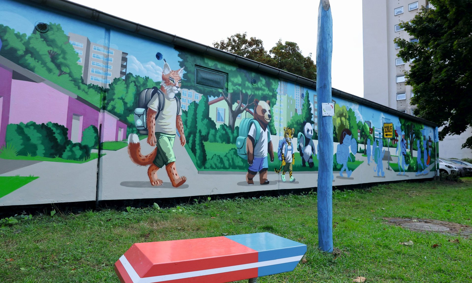 Vorne die Kinderhaltestelle mit Radiergummi-Bank und Riesen-Bleistift, hinten das bunte, meterlange Garagen-Graffiti.