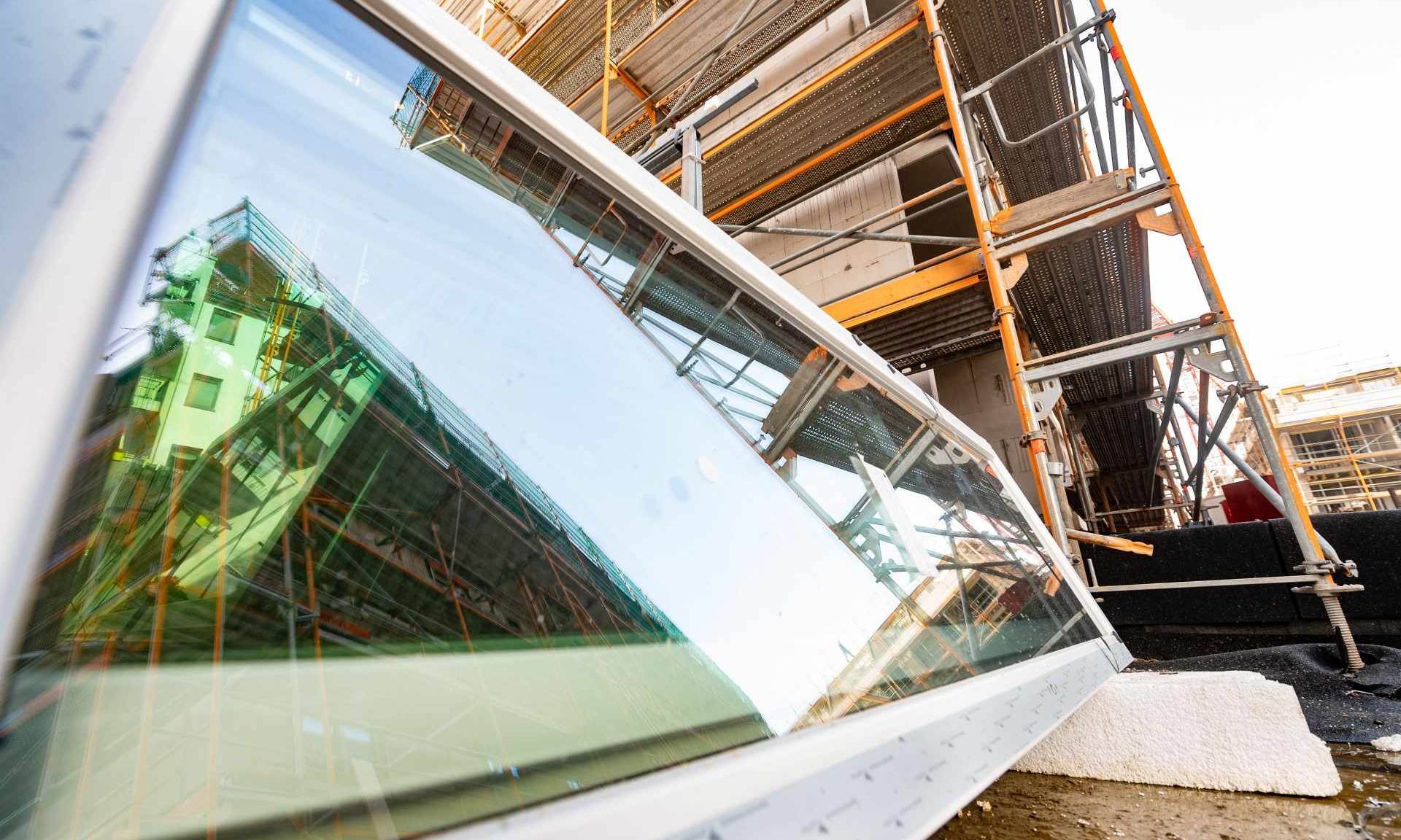 Neues Fenster vor einem Gerüst auf einer Baustelle.