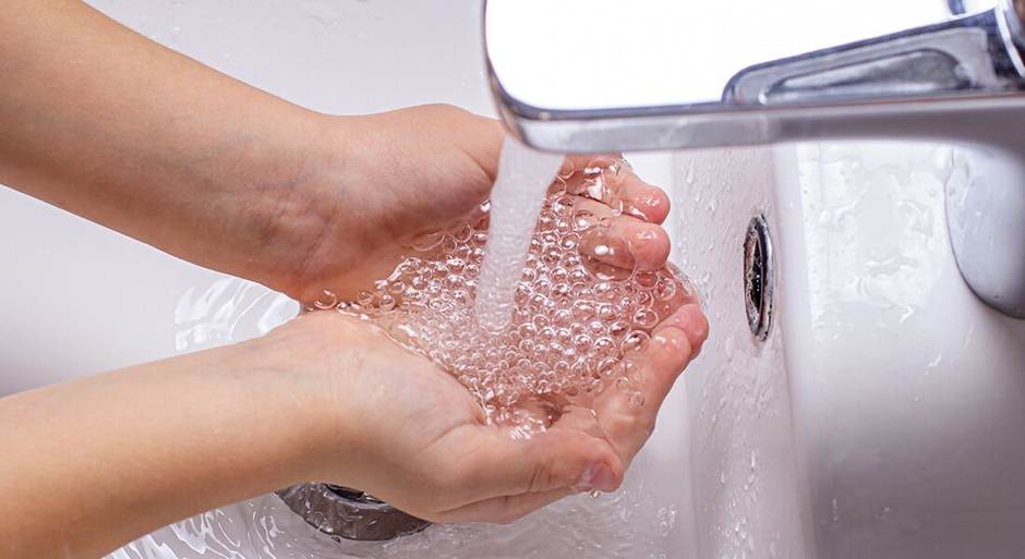 Hände waschen unter fließendem Wasser aus dem Wasserhahn.