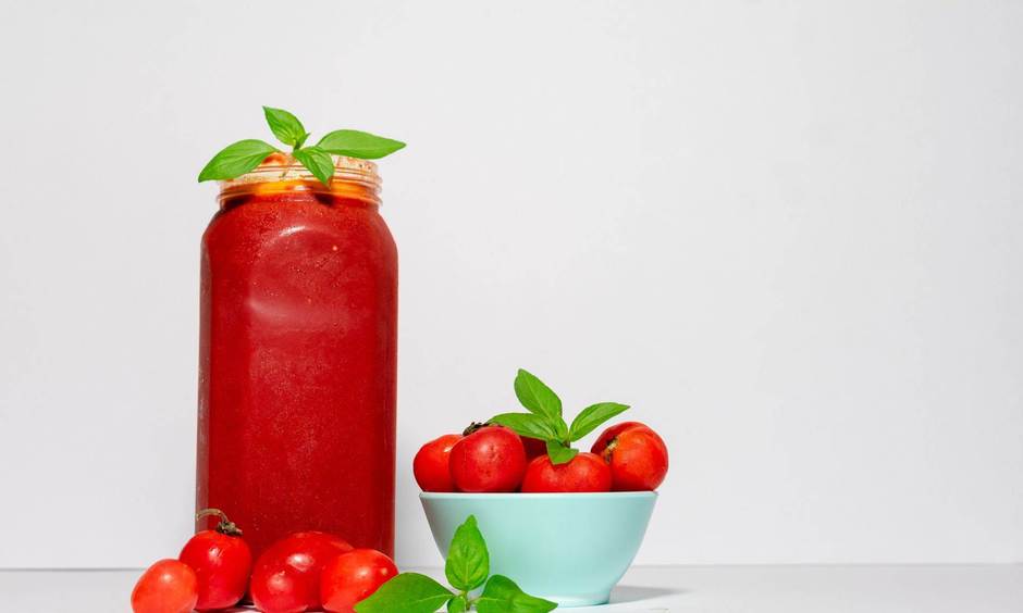 Ketchup im Glas und Schüssel mit Tomaten.