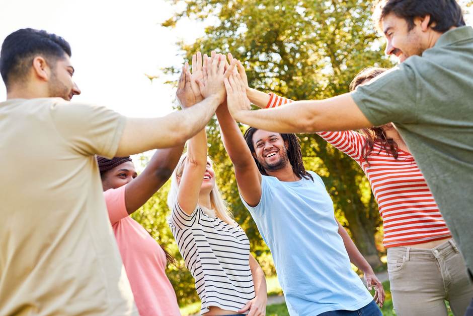 Mehrere Personen sind draußen und geben sich High five.