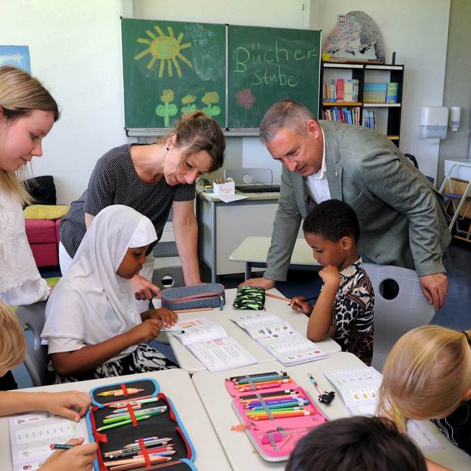 NHW-Regionalcenterleiter Sascha Holstein und Jennifer Linke von der Sozialen Quartiersentwicklung der NHW schauen Kindern der Grundschule Wolfsanger-Hasenhecke beim Lernen über die Schulter. Links Lehramtsstudentin Leonie Barte. 