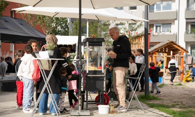 Mann mit Popcornmaschine und Kinder, die Popcorn möchten